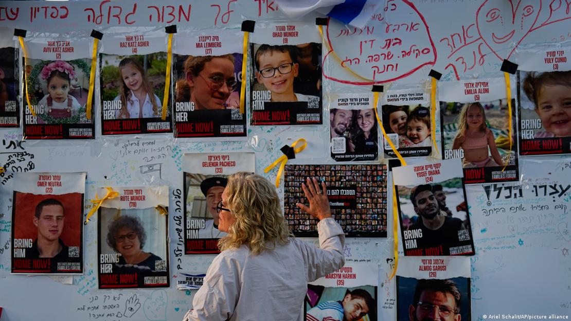 İsrail'in Tel Aviv kentinde, Hamas tarafından kaçırılan kişilerin fotoğraflarının asıldığı panoya dokunan bir kadın - (24.11.2023)